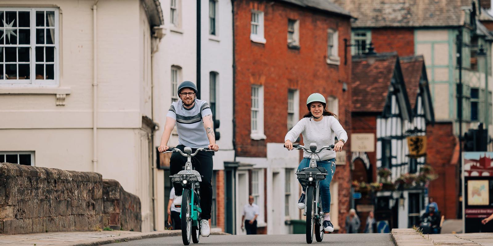 Man and woman riding Beryl bikes along a high street