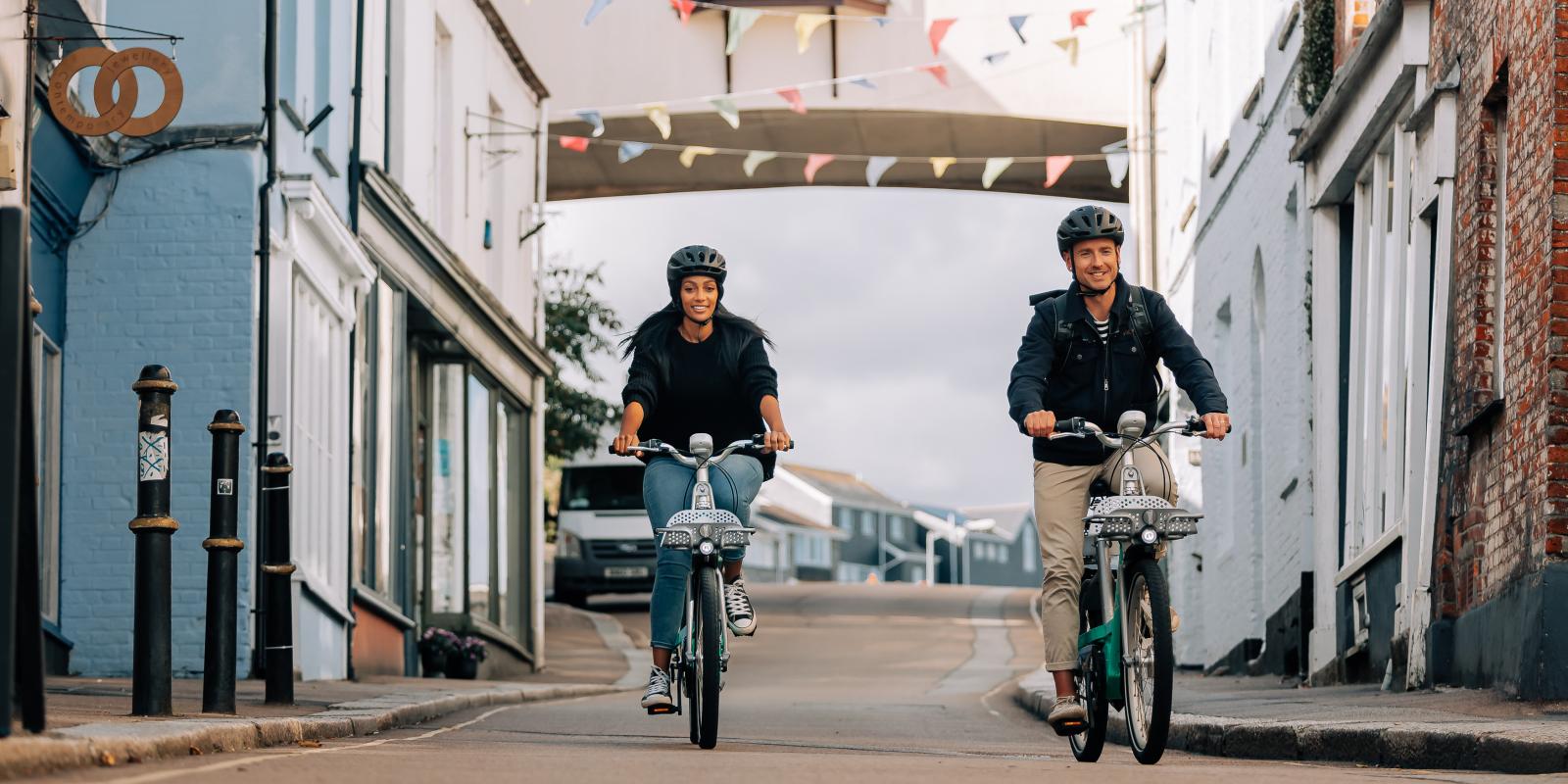 Man and woman riding Beryl bikes along a street in Falmouth Cornwall