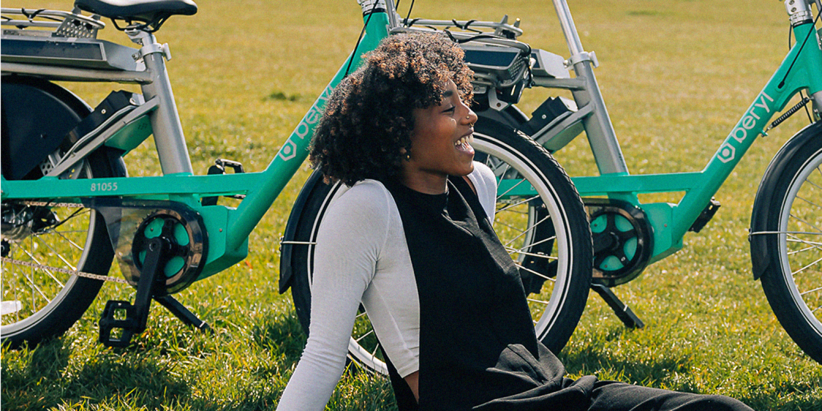 Woman sitting on grass next to bike