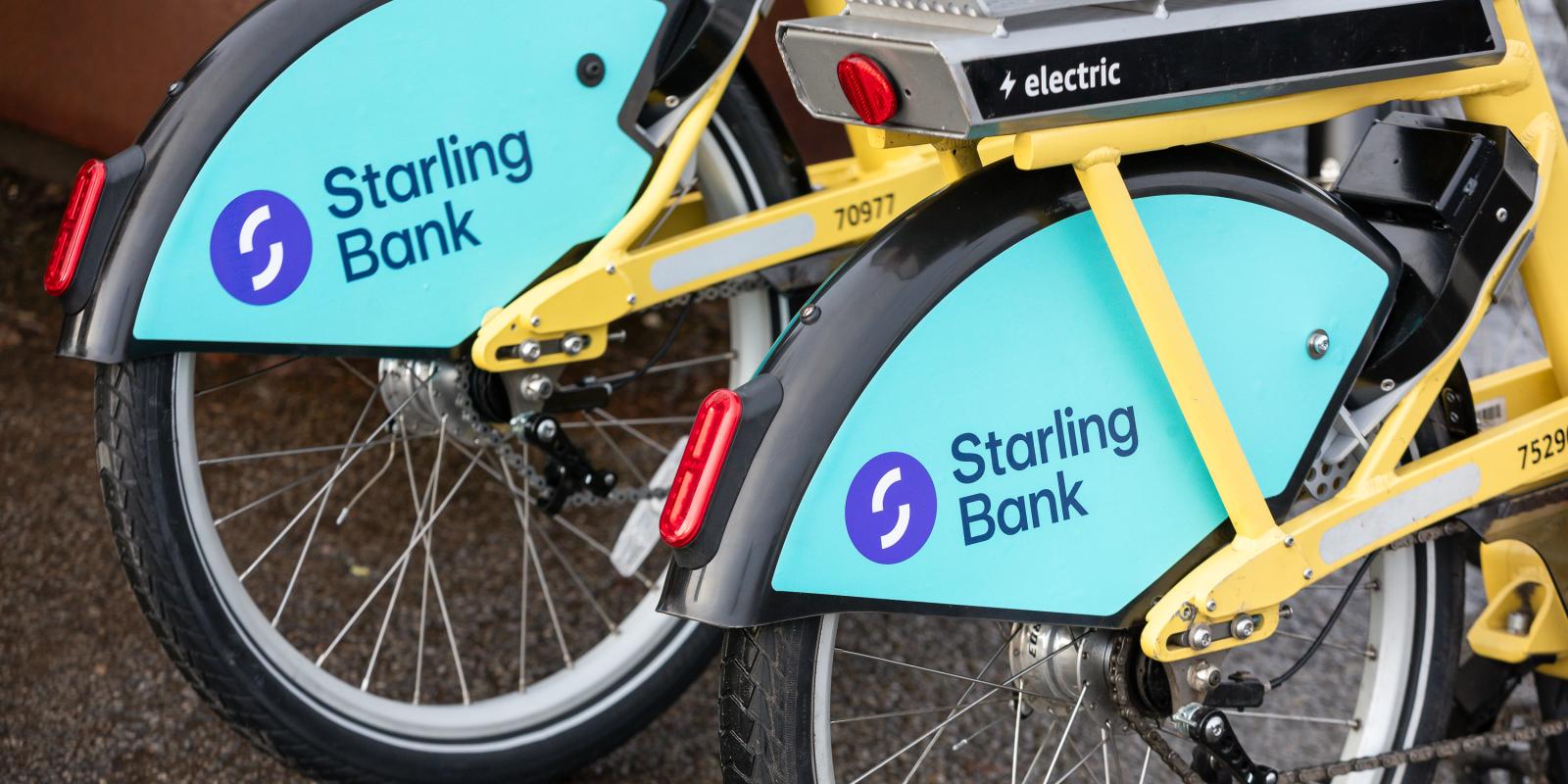 The back wheels of two bikes are visible, they have plastic rear mudguards which have Starling Bank branding on them in turquoise and purple