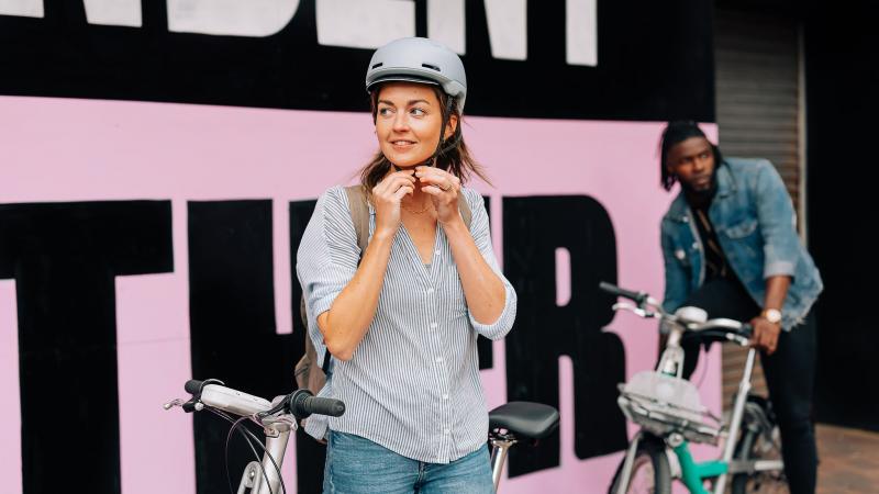 Woman fastening bike helmet to ride a Beryl Bike
