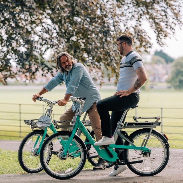 Two men on beryl bikes in the park