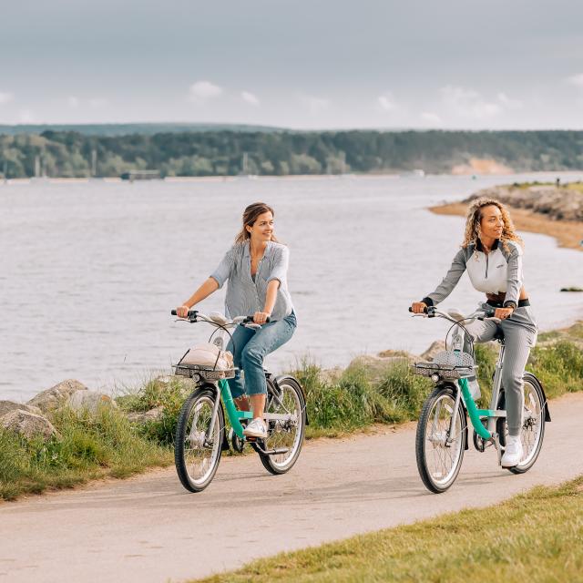 two women riding Beryl bikes along a beach