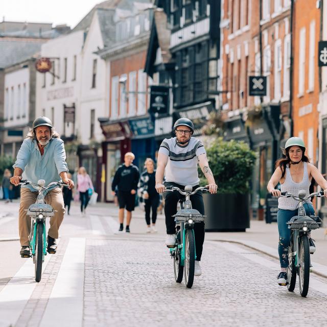Two men and a woman riding Beryl bikes in a high street
