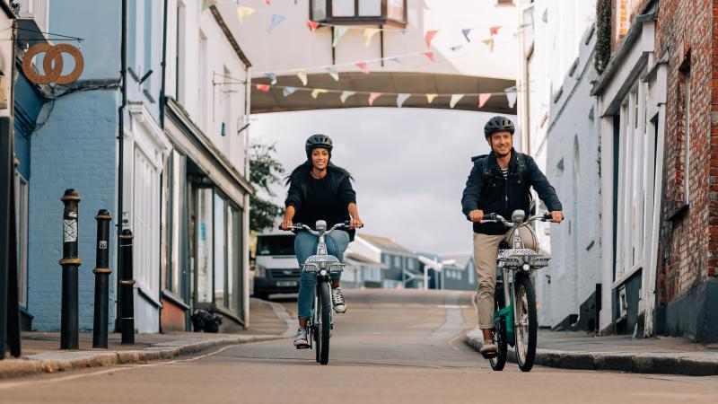 Man and woman riding Beryl bikes along a street in Falmouth Cornwall