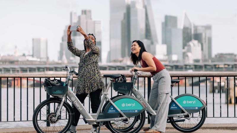 Two riders using Beryl's new BBE2 e-bike with a London cityscape in the background